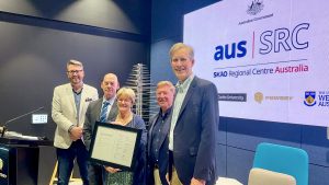 Five people standing together, in the centre is a photo frame holding the AusSRC Partners Agreement.