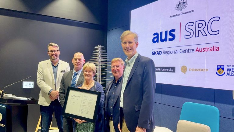 Five people standing together, in the centre is a photo frame holding the AusSRC Partners Agreement.