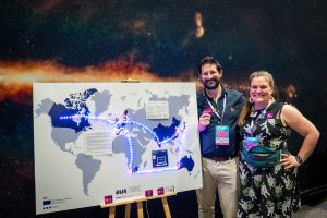 Two people standing next to a world map, lit up by LED lights to show the SRCNet